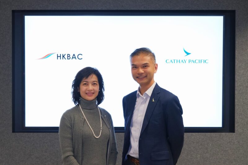 Two people standing together with HKBAC and Cathay Pacific logos displayed behind them.