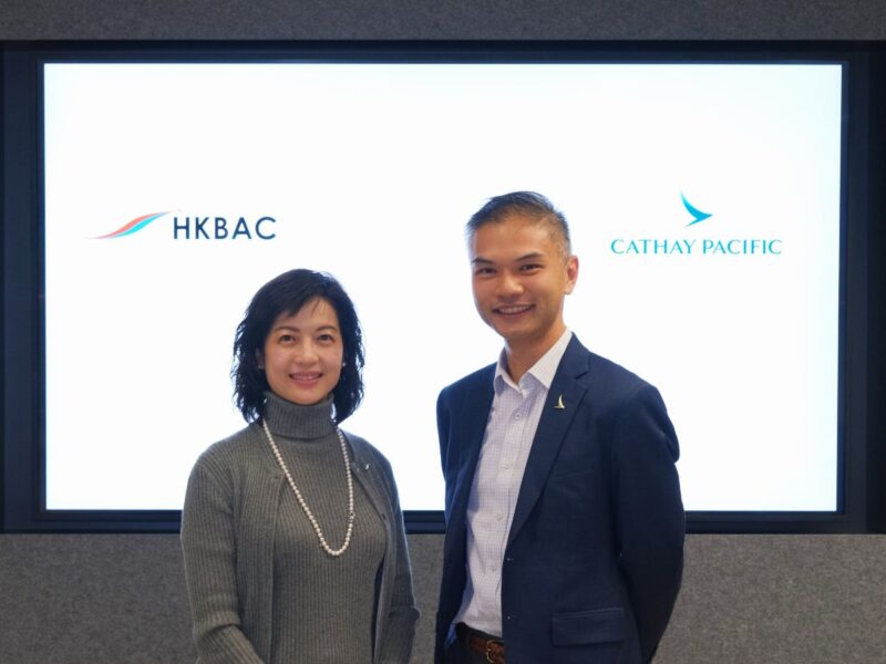Two people standing together with HKBAC and Cathay Pacific logos displayed behind them.